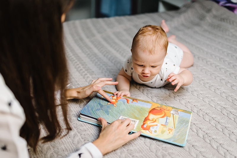 board book on floor with three month old baby looking at it on their tummy
