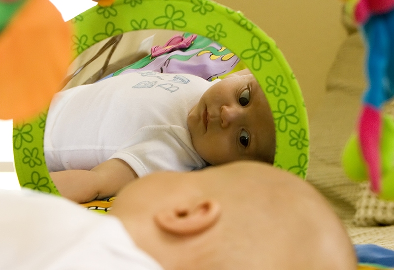 infant looking at themselves in soft mirror