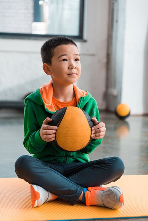 child sitting in a criss cross applesauce position - legs crossed in front of his body