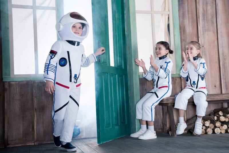 An image of 3 children dressed up as astronauts engaging in cooperative play, which is the 6th stage of the 6 stages of play