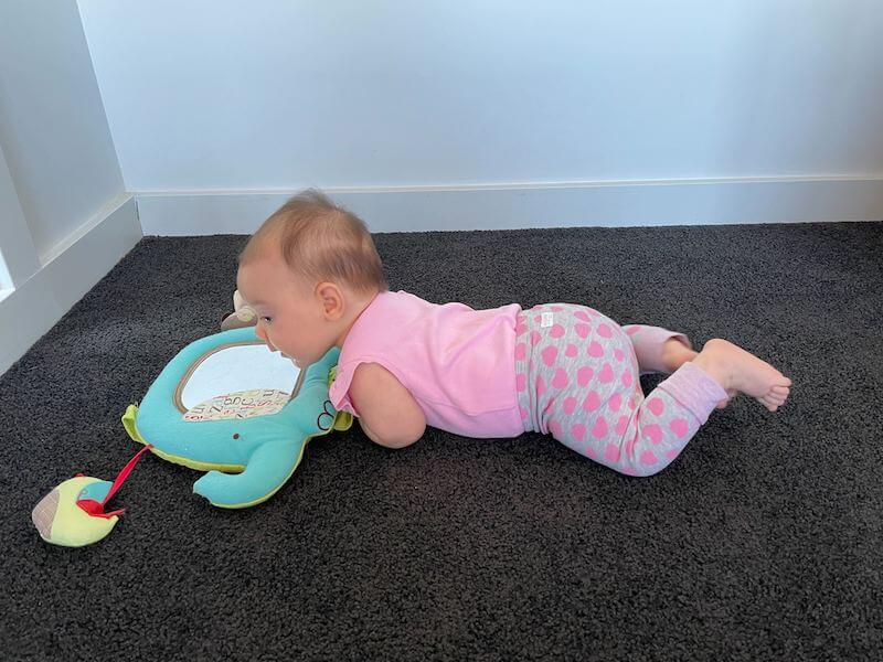 baby lying on tummy with mirror flat on floor in front of her