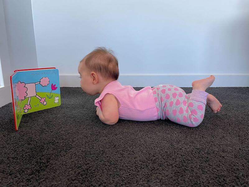 baby on stomach with a soft book propped up in front of them