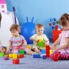 preschool children work on building their own block towers while sitting next to each other