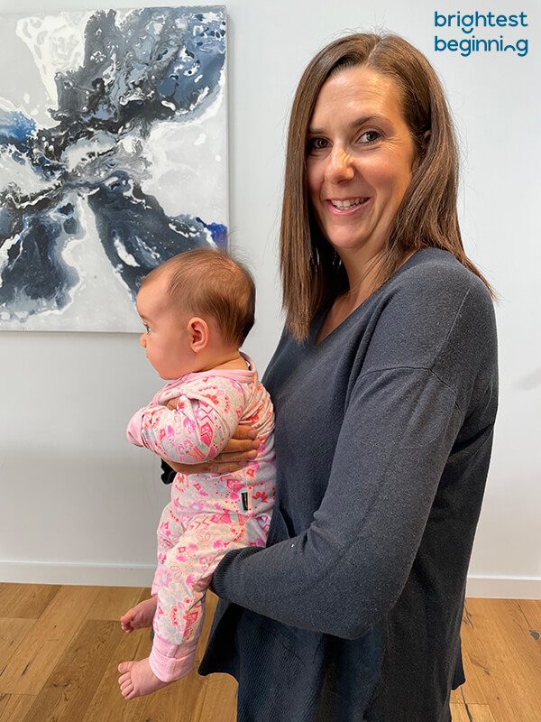 Emma holding an infant in front against her chest with the child facing forwards