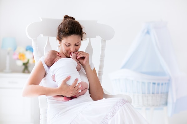 a lady with her baby asleep on her shoulder, sitting in a rocking chair