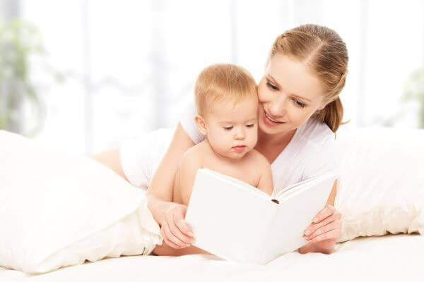 mother reading a book to her young child to calm them before a nap