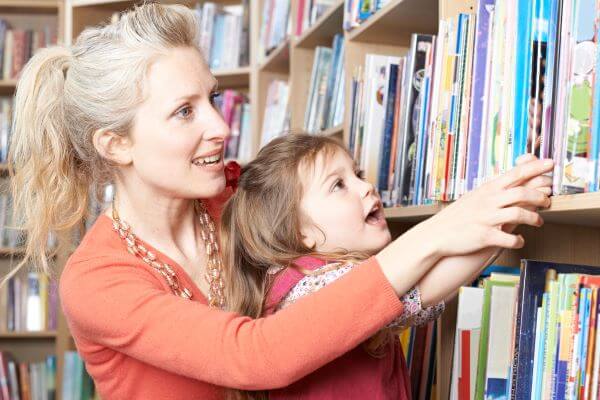 a mother and toddler choosing a book to read from a selection on a shelf