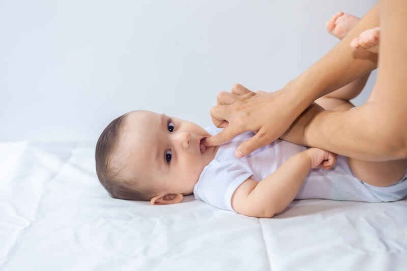 mother with her finger in her baby's mouth massaging her gum to relieve teething pain